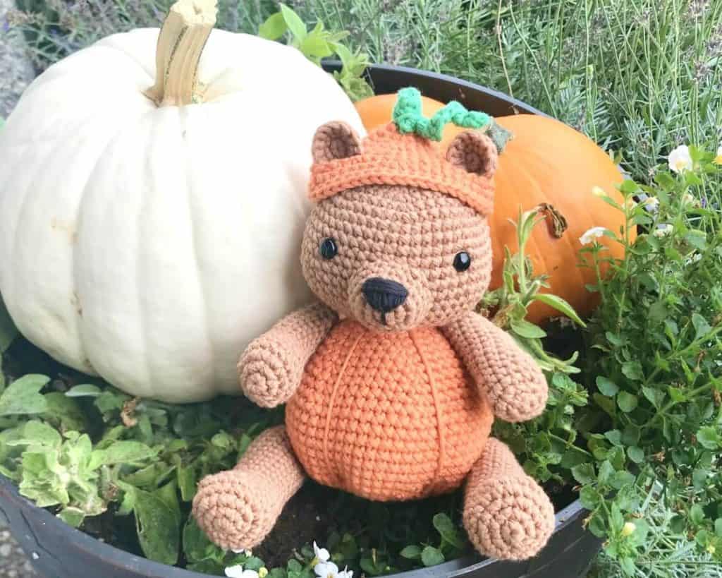 Crochet pumpkin bear sitting with real pumpkins