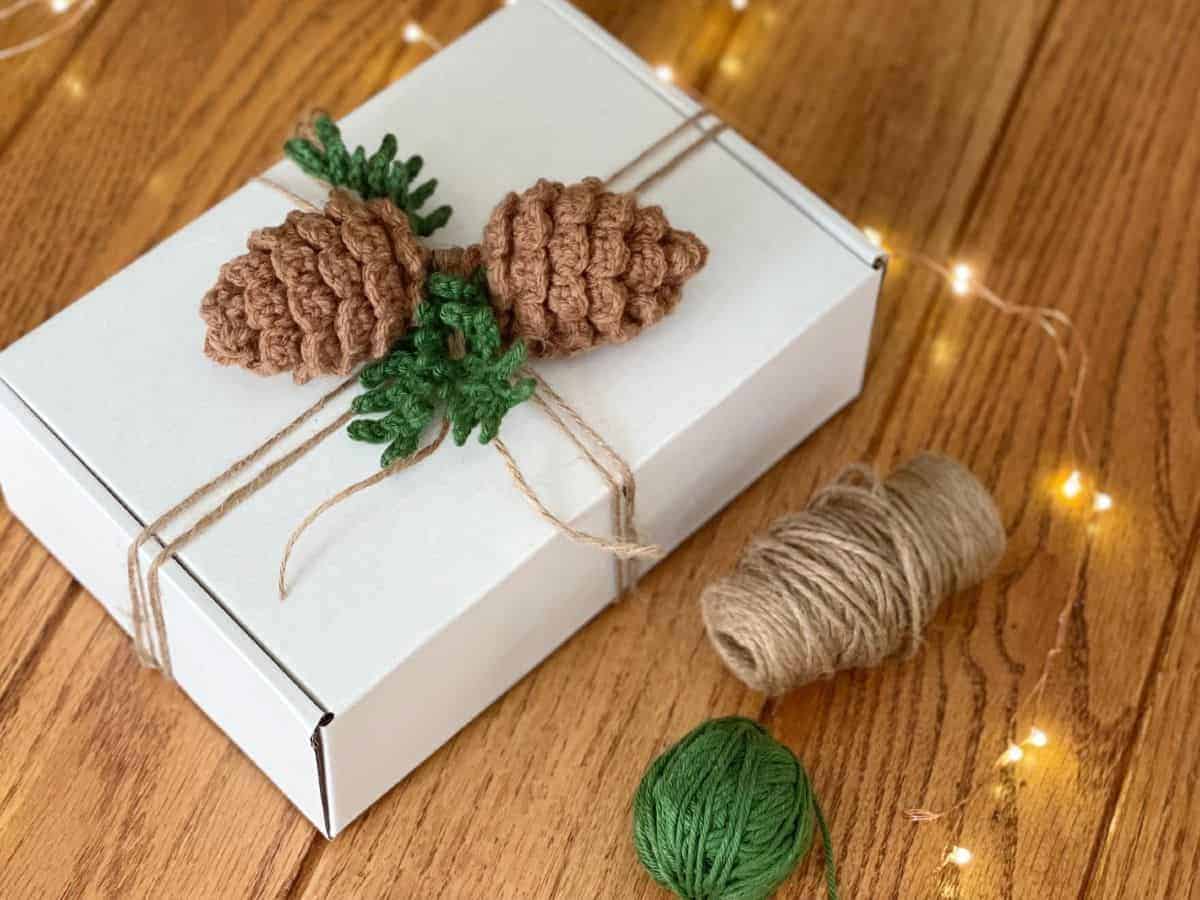 Photo of gift wrapped with crochet pine cones as gift topper