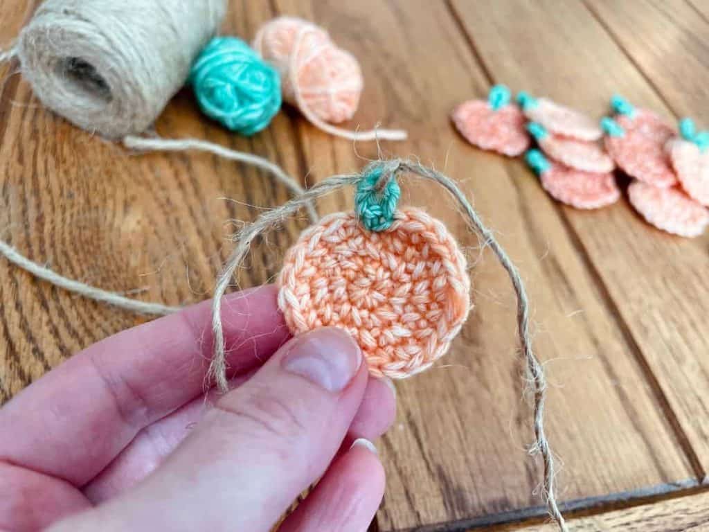 Tying twine to mini pumpkin stems to make garland
