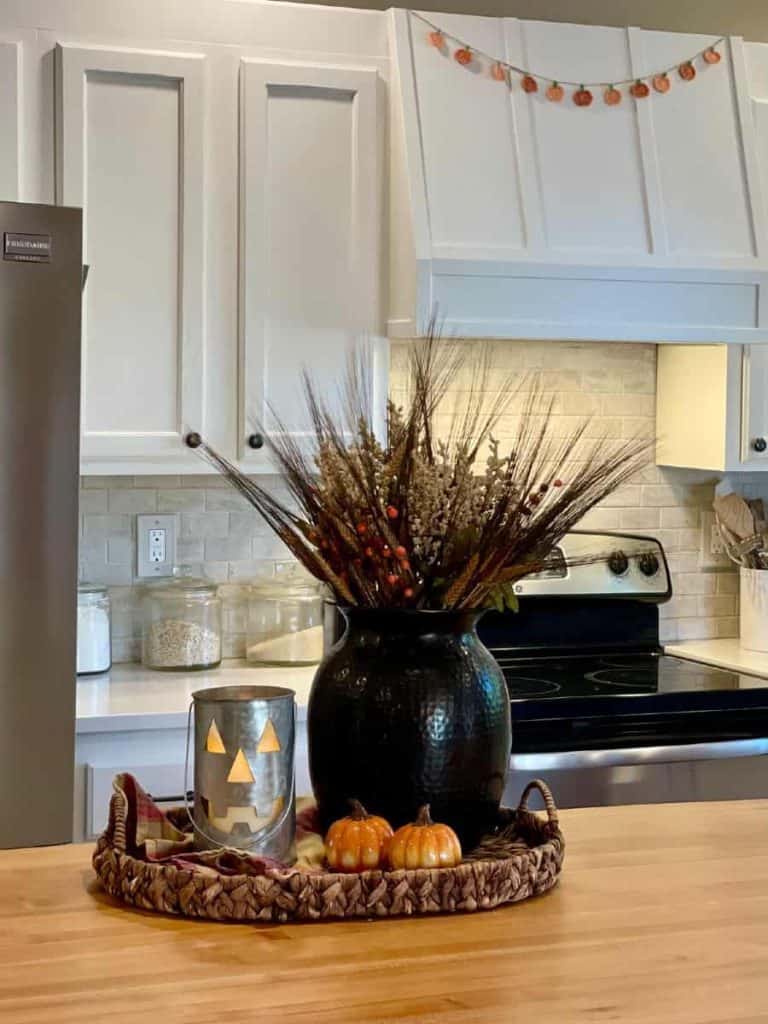Mini crochet pumpkin garland pattern strung across vent hood in kitchen, decorated for fall